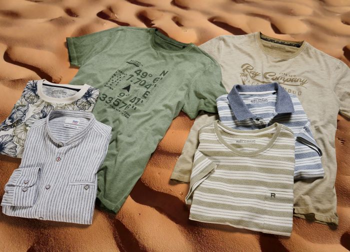 T-Shirts und Hemden liegen auf ordentlich auf einer Sanddüne.
