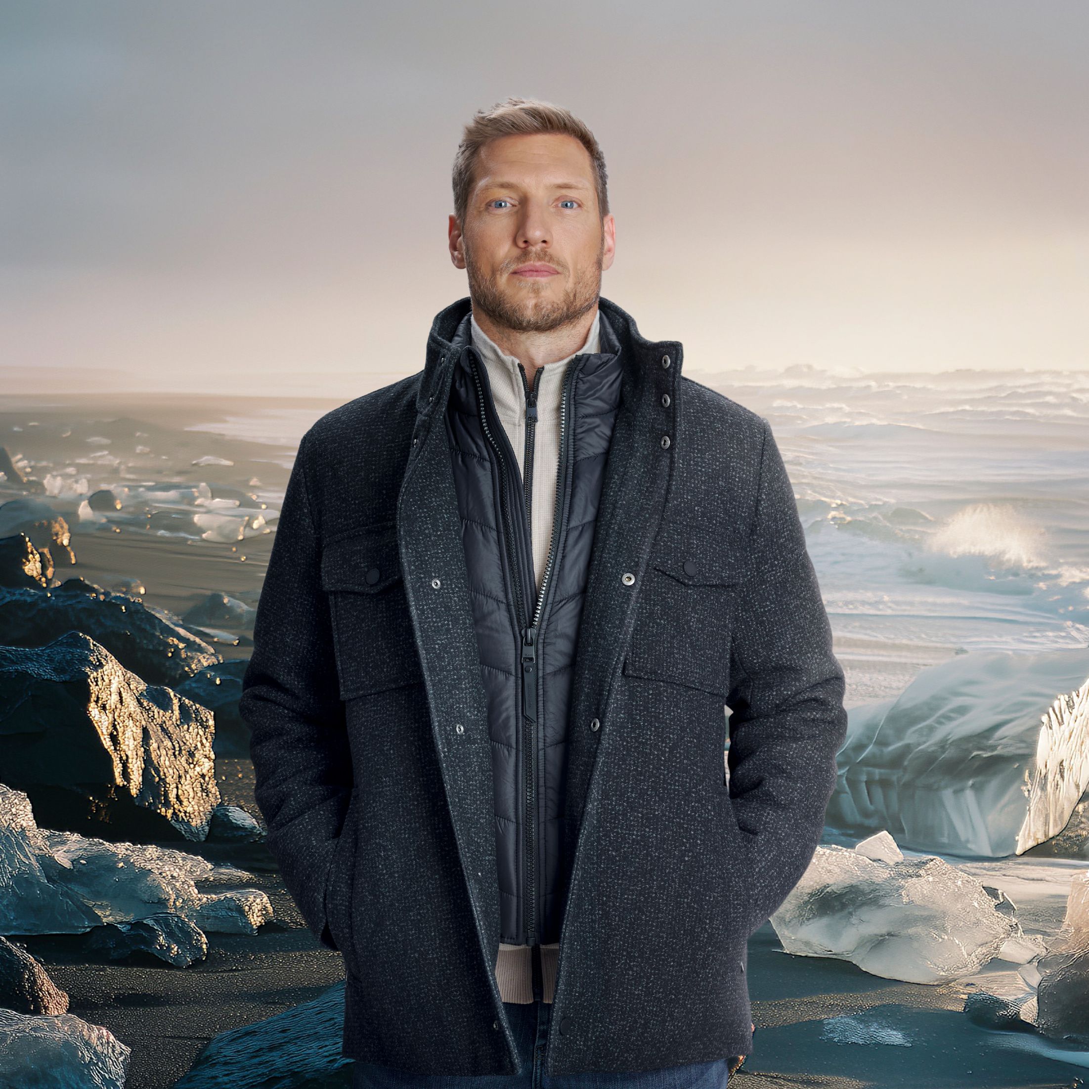 Model in dunkler Winterjacke posiert vor Gletscherlandschaft