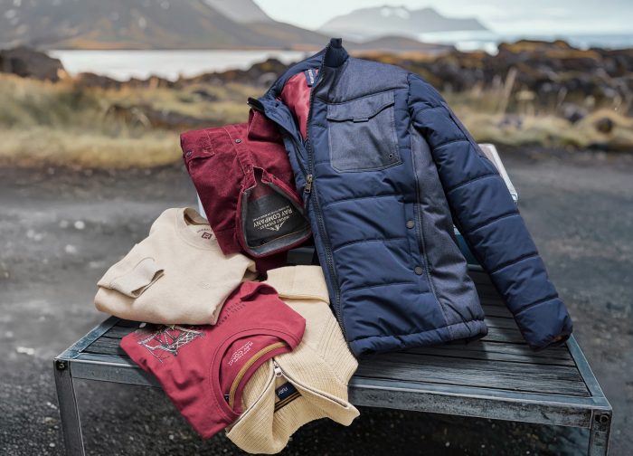 Zusammengelegte Jacke und Pullover in Rot und Blau auf einer Bank im Freien