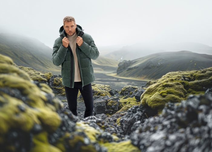 Model in grüner Outdoorjacke mit Kapuze in isländischer Landschaft